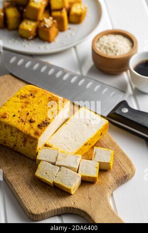 Würfel marinierter Tofu auf Schneidebrett. Stockfoto