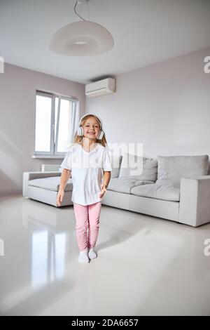 Cute kleine vermissen Spaß beim Stehen vor Graues Sofa Stockfoto