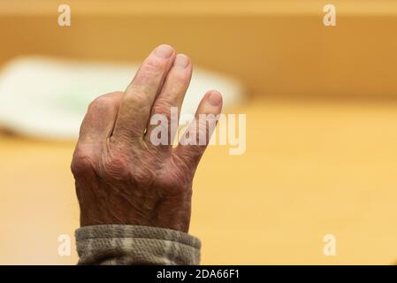 10. November 2020, Bayern, Würzburg: Der Angeklagte hebt die Hand im Gerichtssaal. Ein Prozess gegen einen 92-jährigen Mann, der seine kranke Frau aus Mitleid getötet haben soll, hat am Landgericht Würzburg begonnen. Nach 70 Jahren Ehe soll der Mann seine an Demenz erkrankte Frau erstickt haben, so dass sie nicht in ein Pflegeheim gehen müsste. Foto: Nicolas Armer/dpa Stockfoto