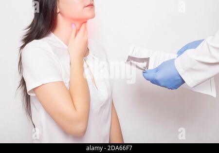 Der Arzt hält die Ergebnisse der Untersuchung der Kehle des Mädchens in seinen Händen. Konzept der Symptome und Halsschmerzen bei Coronavirus. Reinfektion COVID-1 Stockfoto