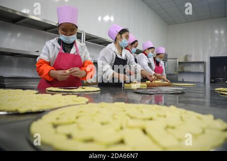 (201110) -- DONGXIANG, 10. November 2020 (Xinhua) -- Dorfbewohner machen am 9. November 2020 in einer Werkstatt zur Armutsbekämpfung des Dorfes Bulenggou im autonomen Bezirk Dongxiang der autonomen Präfektur Linxia Hui, nordwestlich der Provinz Gansu in China, Nahrung. Das Dorf Bulenggou war früher ein stark verarmtes Gebiet. Seit Beginn der Armutsbekämpfung hat sich das Dorf verändert und es gibt eine bessere Infrastruktur, die den Dorfbewohnern Zugang zu Trinkwasser, Straßen, Gesundheitszentrum und gut ausgestatteter Grundschule ermöglicht. Viehzucht hat sich die führende Industrie von Bulenggou Dorf, wo Dorfbewohner wit Stockfoto