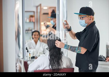 Mann in einer total schwarzen Kleidung kümmert sich um die Haare Stockfoto