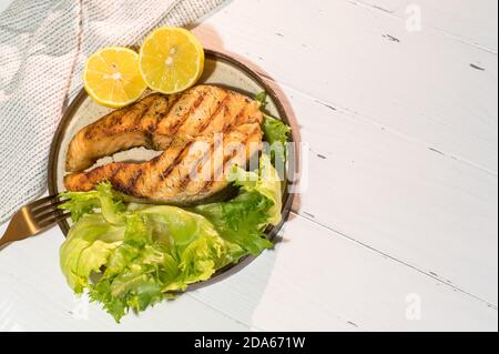 Teller gegrilltes Lachssteak mit Salat auf Holztisch Stockfoto