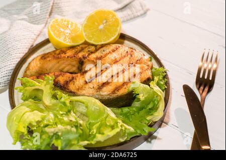 Teller gegrilltes Lachssteak mit Salat auf Holztisch Stockfoto
