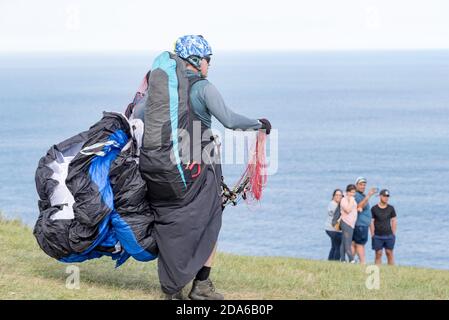 Ein männlicher Gleitschirm mittleren Alters bereitet sich auf den Start am beliebten Startpunkt von bald Hill, Stanwell Tops, New South Wales, Australien vor Stockfoto