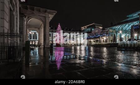 Regen und Reflexionen bei Einbruch der Dunkelheit um den weihnachtsbaum in Covent Garden während der zweiten Sperre in London. Stockfoto