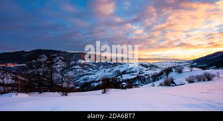 Winter Berglandschaft bei Sonnenaufgang. Bäume und Felder auf schneebedeckten Hügeln. Grat in der Ferne unter einem dramatischen Himmel mit Wolken. Schöne Karpfen Stockfoto
