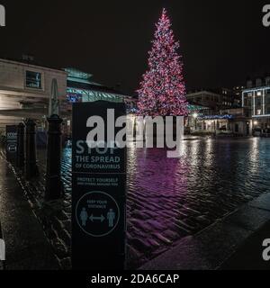 Regen und Reflexionen bei Einbruch der Dunkelheit um den weihnachtsbaum in Covent Garden während der zweiten Sperre in London. Stockfoto