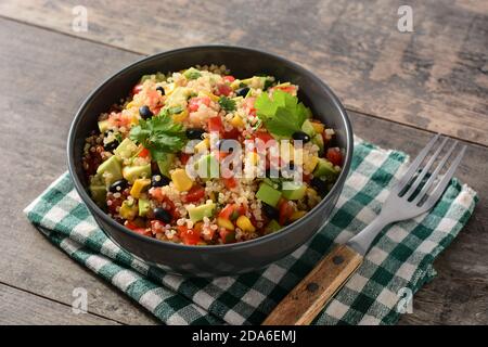 Mexikanischer Salat mit Quinoa in Schüssel auf Holztisch Stockfoto