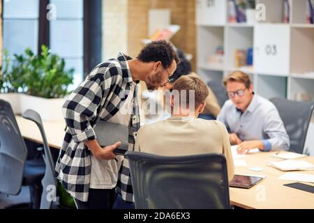 Rückansicht von zwei jungen Kollegen, die im modernen Büro oder Coworking Space gemeinsam etwas diskutieren. Konzept für Teamarbeit und Zusammenarbeit Stockfoto