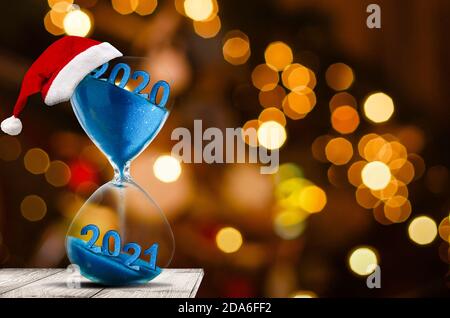 Countdown für Weihnachten. Modernes Sandglas mit Platz für Text, Sand, der durch die Glühbirnen eines Sandglases rieselt. Weihnachtsbaum Lichter als Hintergrund Stockfoto