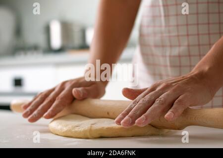 Nahaufnahme einer Frau rollt den Teig mit einem Nudelholz aus. Stockfoto