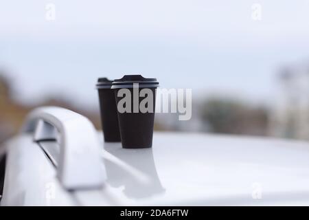 Zwei schwarze Gläser Getränke in einem Stand auf einem verschwommenen Hintergrund der Stadt. Kaffee oder Tee zum Mitnehmen in Einwegbechern. Ein schneller Snack. Kaffeetassen an Stockfoto