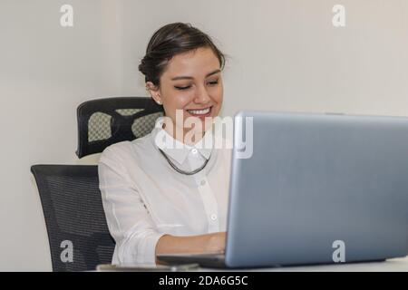 Geschäftsfrau, die im Büro arbeitet und Anrufe macht und verwendet Ihr Laptop und ihr Handy Stockfoto