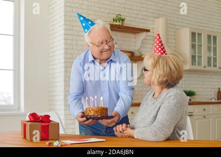 Ein glückliches Seniorenpaar, das ihren Geburtstag oder den Geburtstag der Frau feiert Zu Hause Stockfoto