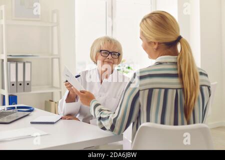 Leitende Ärztin verschreibt Medikamente und gibt dem Patienten ein Rezept. Stockfoto