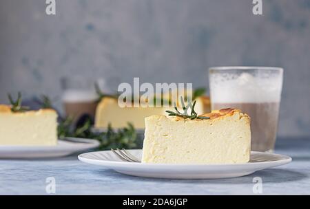 Käsekuchen mit Zitronenvanille, verziert mit Rosmarin-, Minze- und Zitronenscheiben. Ricotta keine Kruste Käsekuchen oder Kasserolle. Blauer Hintergrund. Stockfoto