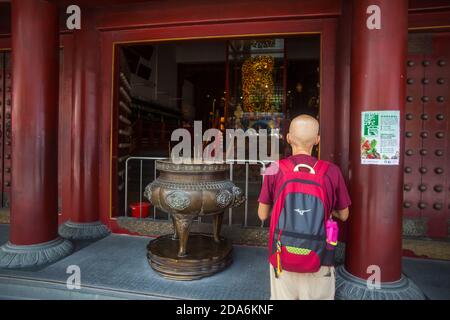 Rückansicht eines älteren Glatzen, der aufrichtig vor der buddhistischen Gottheit betet, chinesischer buddhistischer Religionstempel. Singapur. Stockfoto