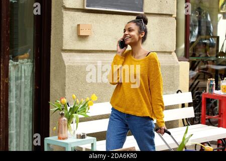 Porträt von lächelnden jungen Afrikanerin Stadtstraße mit Tasche und Handy unterwegs Stockfoto