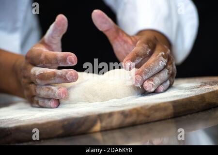 Detail der Hände eines Pizzakochs, der für die verschiedenen Phasen der Vorbereitung einer echten italienischen Pizza hausgemachte mit Hefemehl und Wasser arbeitet. Stockfoto