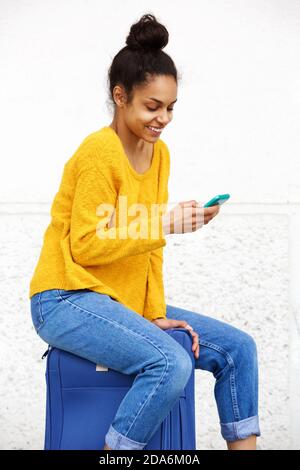 Portrait der schönen jungen Frau mit Handy und sitzen Auf dem Koffer Stockfoto