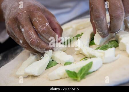 Detail der Hände eines Pizzakochs, der für die verschiedenen Phasen der Vorbereitung einer echten italienischen Pizza hausgemachte mit Hefemehl und Wasser arbeitet. Stockfoto