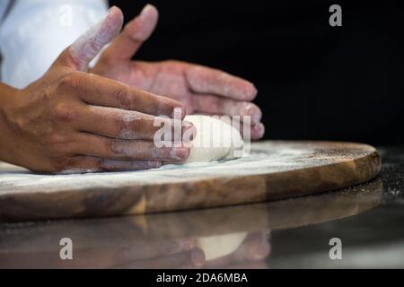 Detail der Hände eines Pizzakochs, der für die verschiedenen Phasen der Vorbereitung einer echten italienischen Pizza hausgemachte mit Hefemehl und Wasser arbeitet. Stockfoto