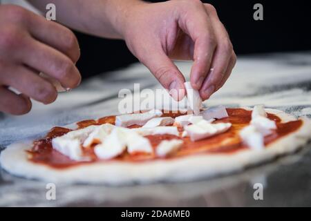 Detail der Hände eines Pizzakochs, der für die verschiedenen Phasen der Vorbereitung einer echten italienischen Pizza hausgemachte mit Hefemehl und Wasser arbeitet. Stockfoto