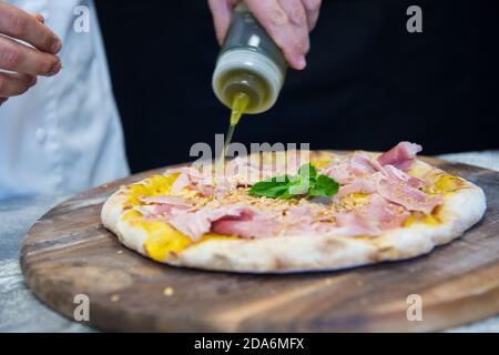 Detail der Hände eines Pizzakochs, der für die verschiedenen Phasen der Vorbereitung einer echten italienischen Pizza hausgemachte mit Hefemehl und Wasser arbeitet. Stockfoto