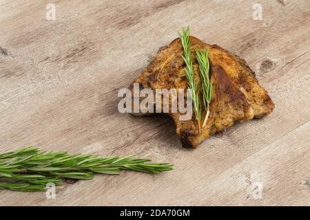 Köstliches Stück Braten mit einem Zweig Rosmarin Auf einem hölzernen Hintergrund Stockfoto