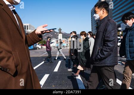 Menschen, die Schutzmasken als vorbeugende Maßnahmen gegen Coronavirus tragen, überqueren in Seoul die Straße. Stockfoto