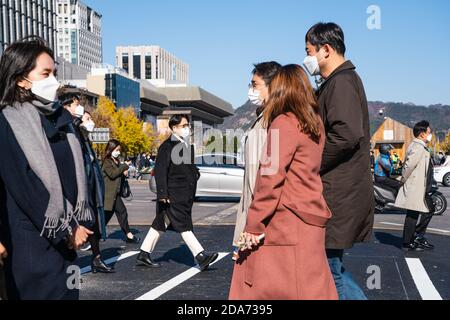 Menschen, die Schutzmasken als vorbeugende Maßnahmen gegen Coronavirus tragen, überqueren in Seoul die Straße. Stockfoto