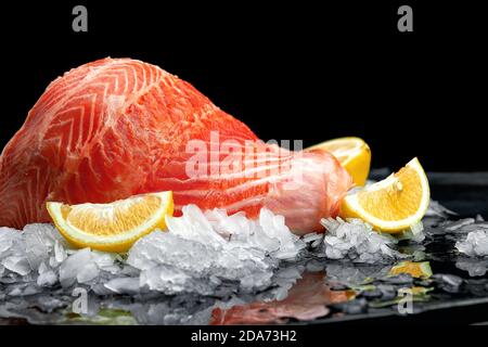 Frisches, rohes Lachsfischsteak auf Eis auf dunklem Steingrund. Kreatives Layout aus Fisch, Draufsicht, Flachlage Stockfoto