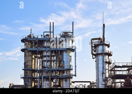 Alte Destillationskolonne Türme mit blauem Himmel mit Wolken Hintergrund bei chemischen Anlage. Außenansicht von Silber Metall rostigen Methanol Destillation Unternehmen Stockfoto