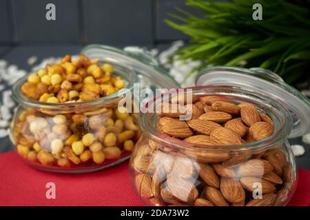 Geschälte Mandeln und gemischte Nüsse in zwei Gläsern. Nahrhafte Snacks Stockfoto