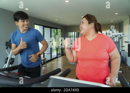 Zwei asiatische Trainer Mann und übergewichtige Frau Training Ausbildung auf dem Laufband im Fitnessstudio, Trainer thump bis zu ihr für gutes Ergebnis während des Trainings. Dicke Frauen Stockfoto