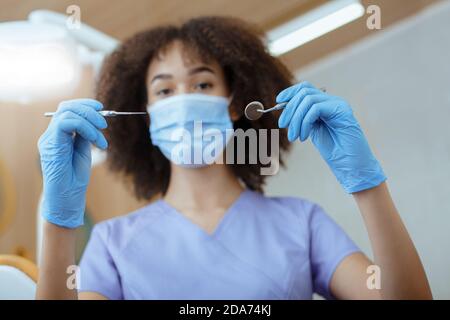 afroamerikanische Frau in Uniform hält medizinische Instrumente zur Untersuchung Des Patienten Stockfoto