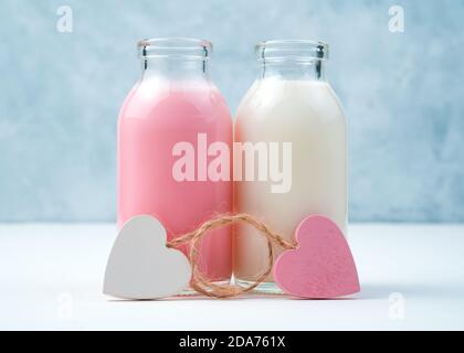 Milchshakes in Flaschen und Herzen auf blauem und weißem Hintergrund. Stockfoto