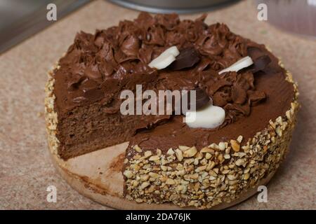 Schokoladenkuchen mit Sahne und Erdnüssen. Dekoriert mit Schokoladenherzen. Auf Kiefernbrettern. Stockfoto