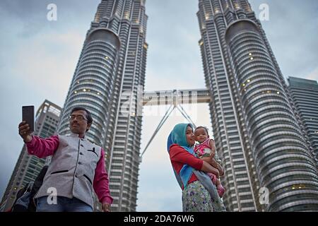 Kuala Lumpur, Malaysia, Februar 2016. Eine Familie, die ein Selfie mit den Petronas macht, steht hinter ihnen. Stockfoto