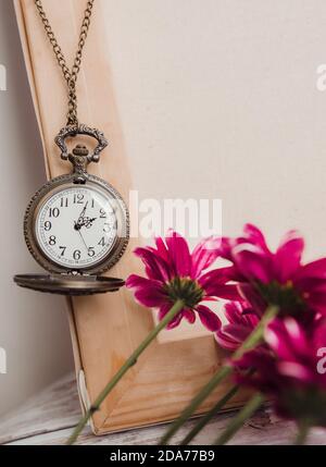 Alte runde Vintage-Uhr auf einer Kette zwischen Blumen in Der Innenraum Stockfoto