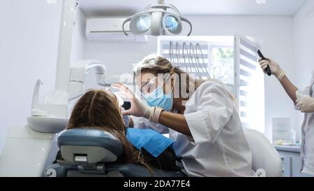 Junge Frau Zahnarzt. Empfang beim Kieferorthopäden. Austausch der Zahnspangen. Polieren. Gelverklebung. Stockfoto