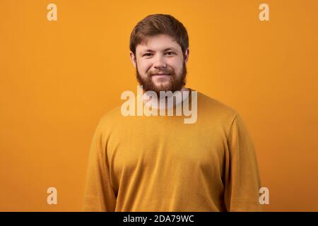 Headshot von rothaarigen seriösen jungen Blogger schaut selbstbewusst in die Kamera, denkt über neue Inhalte seiner Webseite, lässig gekleidet, verdient Geld Stockfoto