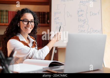 Englischlehrer sitzt am Tisch und erklärt den Schülern die Lektion Stockfoto