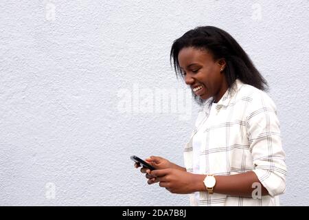Seitenportrait von glücklichen afrikanischen Frau SMS an Freunde von Handy. Stockfoto