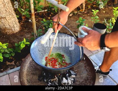 Ungarische Gulyas Leves, Gulasch, in einem Kessel, Bogracs, im Garten - Kochen der Zwiebeln und Paprika Stockfoto
