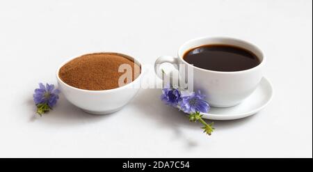 Chicorée Getränk und Pulver in einer Schüssel auf weißem Hintergrund. Blaue Zichorien Blumen. Kaffeersatz. Seitenansicht. Stockfoto