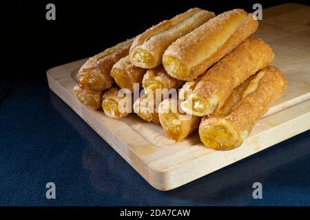 Die Sweet Sticks sind mit Füllung auf Glastisch ruhen. Das Dessert zum Tee auf schwarzem Hintergrund. Stockfoto