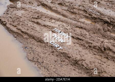 Die Worte glücklich neuen Schmutz gelegt mit silbernen Metall-Buchstaben Auf nasser Schlammoberfläche Stockfoto