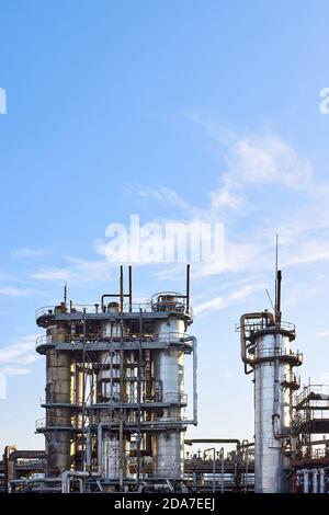 Alte Destillationskolonne Türme mit blauem Himmel mit Wolken Hintergrund bei chemischen Anlage. Außenansicht von Silber Metall rostigen Methanol Destillation Unternehmen Stockfoto